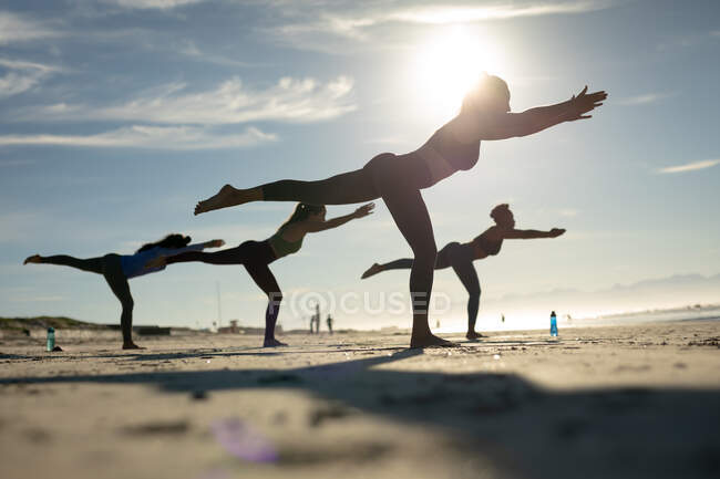 Gruppe verschiedener Freundinnen, die Yoga am Strand praktizieren. gesunder aktiver Lebensstil, Fitness im Freien und Wohlbefinden. — Stockfoto
