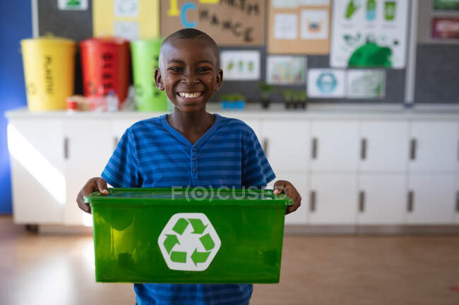 Портрет африканского мальчика с подносом, заполненным пластиковыми предметами, пригодными для вторичной переработки в школе. школа и концепция образования — стоковое фото