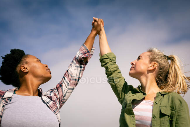 Zwei fröhliche Freundinnen, die sich an einem sonnigen Tag an den Händen halten. Freundinnen-Bonding am Strand. — Stockfoto