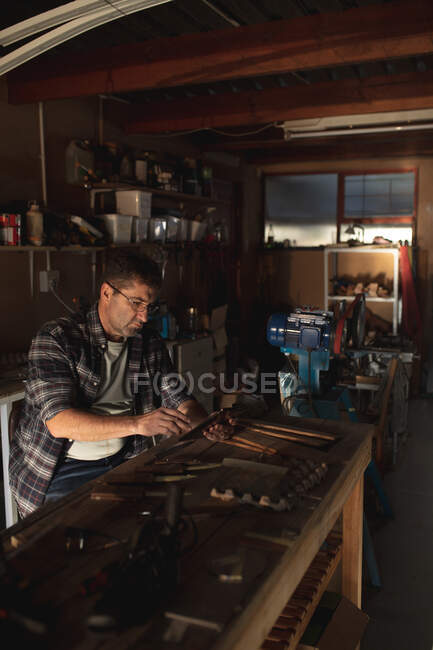 Kaukasischer Messermacher sitzt am Schreibtisch und benutzt Tabletten in der Werkstatt. unabhängiger Kleinunternehmer bei der Arbeit. — Stockfoto