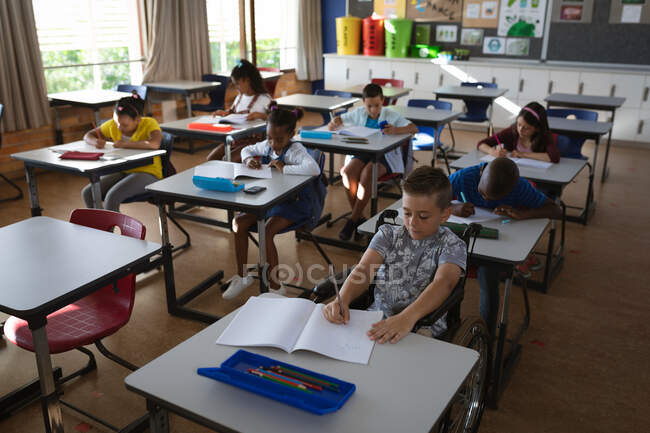 Grupo de estudantes diversos que estudam enquanto estão sentados em sua mesa na classe na escola. conceito de escola e educação — Fotografia de Stock