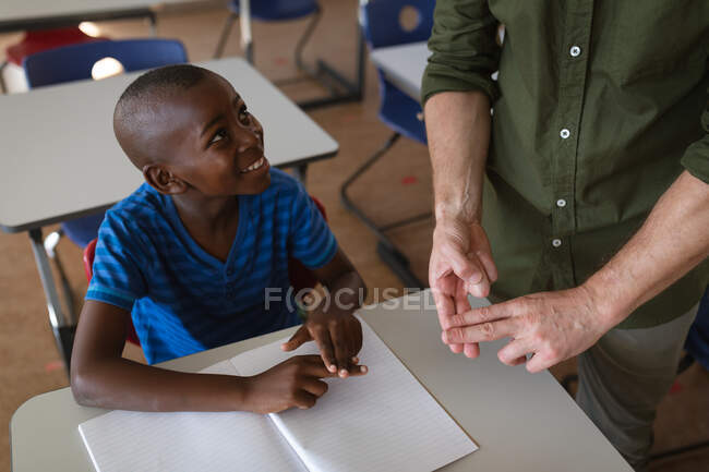 У середній школі чоловік говорить мовою жестів разом з хлопчиком - афроамериканцем. школа і освіта — стокове фото