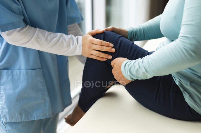 Female physiotherapist treating female patient at her home. healthcare and medical physiotherapy treatment. — Stock Photo