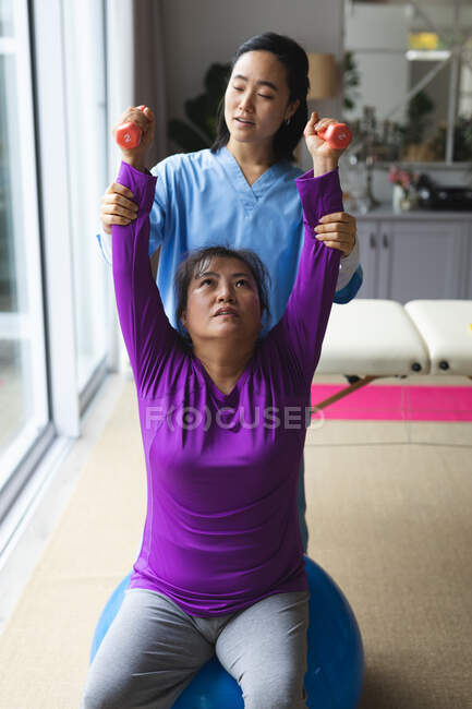 Азиатская женщина-физиотерапевт лечит азиатскую пациентку у себя дома. медицинское и физиотерапевтическое лечение. — стоковое фото