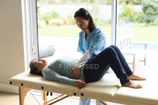 Fisioterapeuta asiática tratando a paciente idosa em sua casa. tratamento de saúde e fisioterapia médica. — Fotografia de Stock