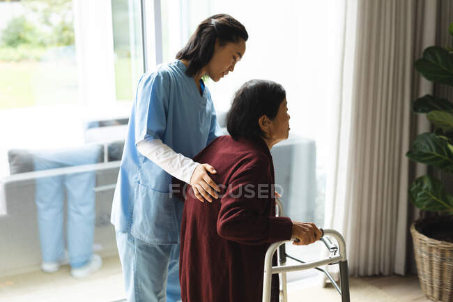 Азиатская женщина-физиотерапевт лечит пожилую пациентку у себя дома. медицинское и физиотерапевтическое лечение. — стоковое фото