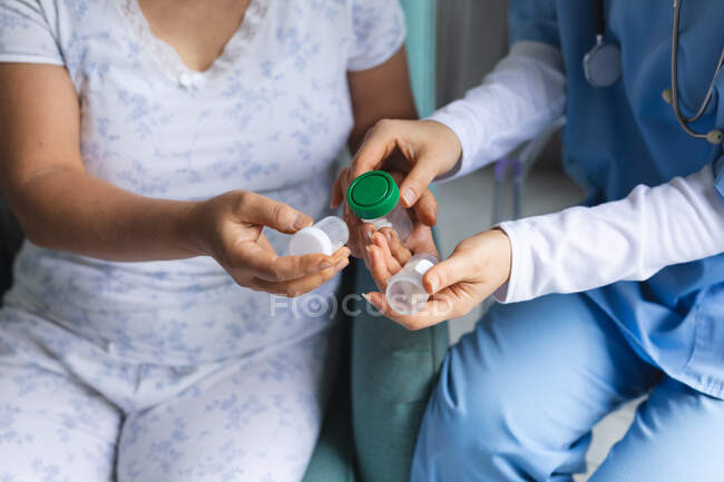 Female doctor giving box of pills female patient at home. healthcare and medical physiotherapy treatment. — Stock Photo