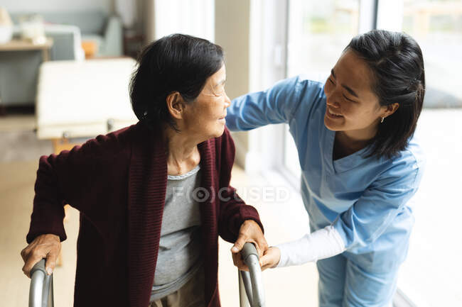 Fisioterapista asiatica che cura una paziente anziana a casa sua. cure sanitarie e fisioterapiche. — Foto stock