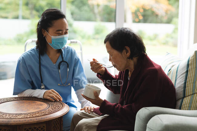 Азиатская женщина-физиотерапевт в маске для лица и лечит пожилую пациентку. медицинское и физиотерапевтическое лечение. — стоковое фото
