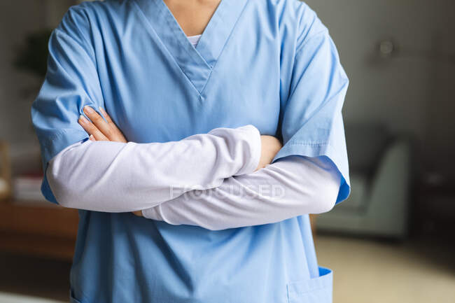 Женщина-физиотерапевт, стоящая со скрещенными руками дома перед лечением. медицинское и физиотерапевтическое лечение. — стоковое фото