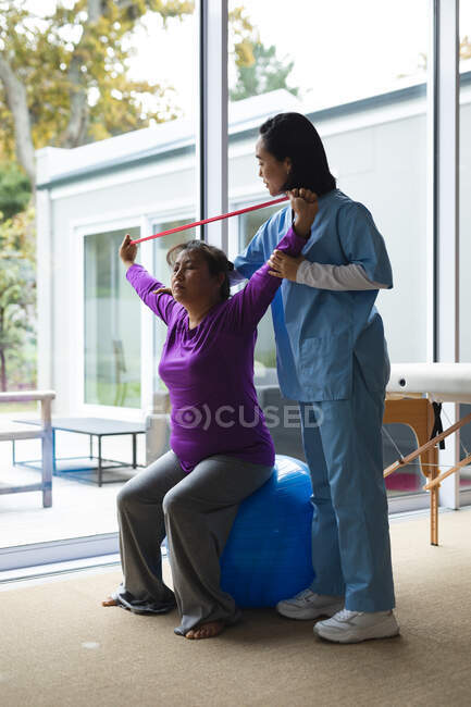 Eine asiatische Physiotherapeutin behandelt eine asiatische Patientin zu Hause. Gesundheitswesen und medizinische physiotherapeutische Behandlung. — Stockfoto