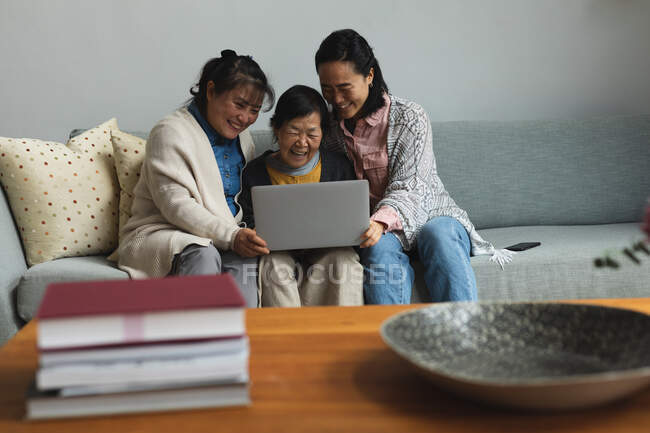 Glückliche ältere asiatische Frau zu Hause mit erwachsener Tochter und Enkelin mit Laptop. Seniorenleben, Zeit zu Hause mit der Familie verbringen. — Stockfoto