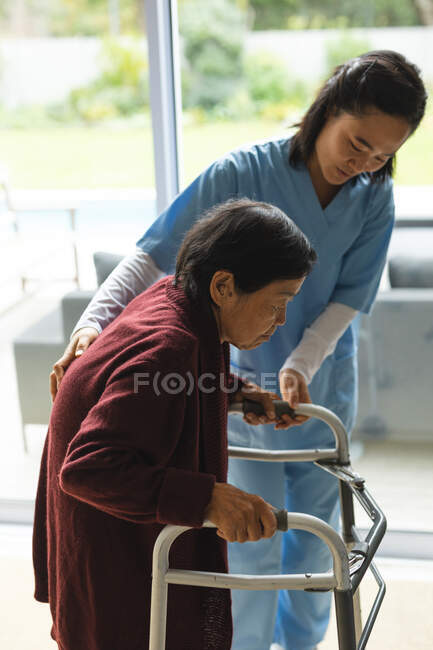 Fisioterapeuta asiática que trata a una paciente mayor en su casa. atención médica y fisioterapia médica tratamiento. - foto de stock
