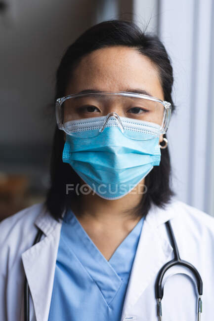 Ritratto di dottoressa asiatica con maschera facciale a casa. cure sanitarie e fisioterapiche. — Foto stock