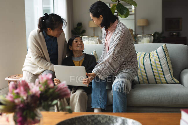 Feliz sênior asiático mulher em casa com adulto filha e neta usando laptop. estilo de vida sênior, passar tempo em casa com a família. — Fotografia de Stock