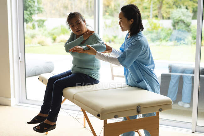 Fisioterapeuta asiática tratando a paciente idosa em sua casa. tratamento de saúde e fisioterapia médica. — Fotografia de Stock