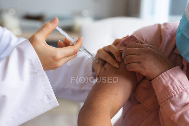 Doctora y vacunando a la paciente femenina en casa. atención médica y fisioterapia médica tratamiento. - foto de stock