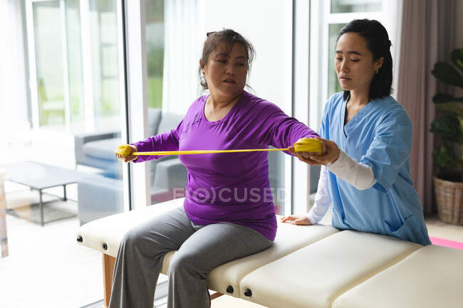 Fisioterapista asiatica che cura una paziente asiatica a casa sua. cure sanitarie e fisioterapiche. — Foto stock