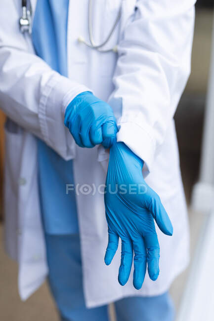 Medico donna che indossa guanti medici a casa prima del trattamento. cure sanitarie e fisioterapiche. — Foto stock