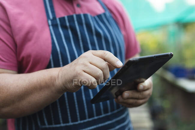 Hands of male gardener using tablet at garden centre. specialist working at bonsai plant nursery, independent horticulture business. — Stock Photo