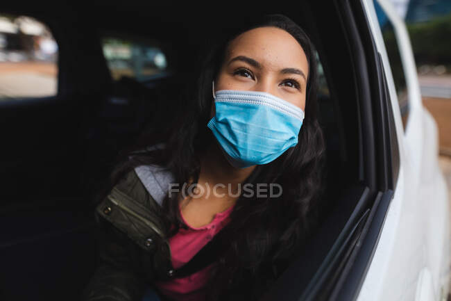 Азиатка в маске сидит в такси. Независимая молодая женщина вне и около в городе во время коронавируса ковид 19 пандемии. — стоковое фото