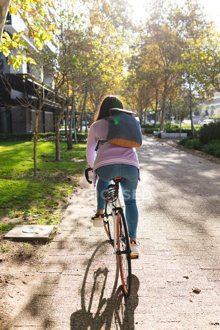 Asiatin beim Fahrradfahren im sonnigen Park. Unabhängige junge Frau in der Stadt unterwegs. — Stockfoto