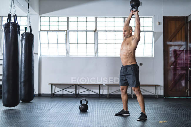 Сильный кавказский мужчина тренируется в спортзале, поднимает тяжести. силовые и фитнес-кросс тренировки для бокса. — стоковое фото