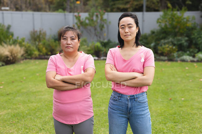 Porträt einer älteren asiatischen Frau im Freien mit erwachsener Tochter, die Brustkrebs-Bewusstseinsbänder trägt. Brustkrebs-Bewusstsein, Zeit zu Hause mit der Familie verbringen. — Stockfoto