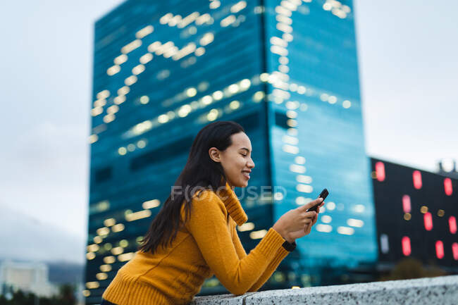 Mulher asiática usando smartphone e sorrindo na rua. jovem independente para fora e sobre na cidade. — Fotografia de Stock