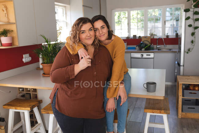 Portrait of lesbian couple smiling and embracing in kitchen. domestic lifestyle, spending free time at home. — Stock Photo