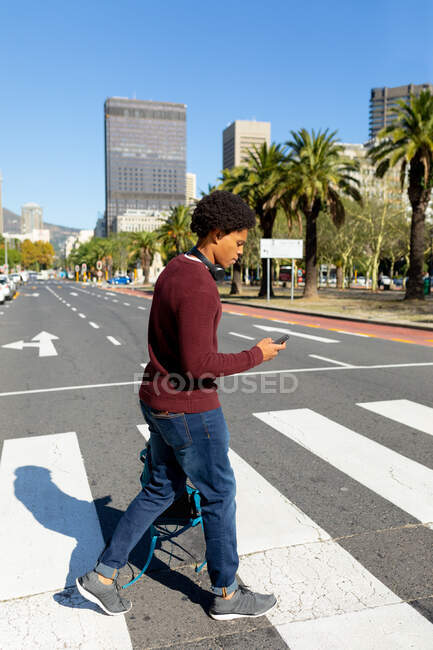 Uomo afroamericano in città utilizzando smartphone e camminare. nomade digitale in movimento, in giro per la città. — Foto stock