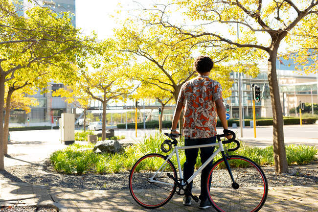 Un afroamericano in citta 'con la bici in mano. nomade digitale in movimento, in giro per la città. — Foto stock