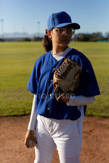 Смешанная раса женщина бейсбольный кувшин на солнечном бейсбольном поле готовится бросить мяч во время игры. женская бейсбольная команда, спортивная подготовка и тактика игры. — стоковое фото