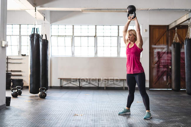 Forte donna caucasica che si allena in palestra, solleva pesi. training incrociato di forza e fitness per la boxe. — Foto stock
