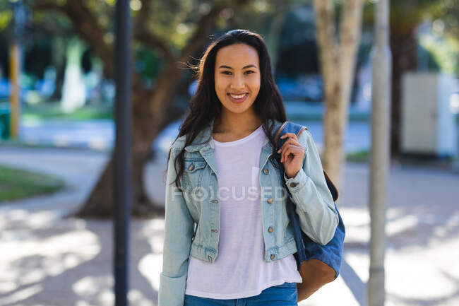 Портрет усміхненої азійської жінки, яка дивиться на камеру в сонячному парку. Незалежна молода жінка у місті.. — стокове фото