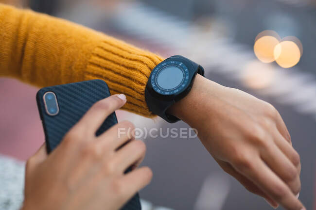 Woman checking smartwatch and holding smartphone in the street. independent young woman out and about in the city. — Stock Photo
