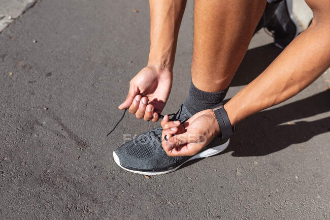 Hombre en forma haciendo ejercicio en la ciudad atando zapatos en la calle. fitness y estilo de vida urbano activo al aire libre. - foto de stock