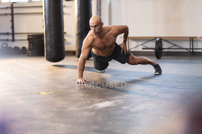 Strong caucasian man exercising at gym, doing push-ups using one hand. strength and fitness cross training for boxing. — Stock Photo