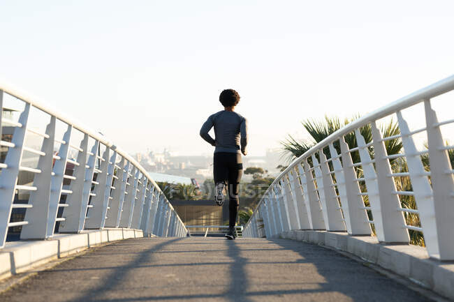 Un uomo afroamericano in forma che si allena in citta 'correndo per strada. fitness e stile di vita urbano attivo all'aperto. — Foto stock