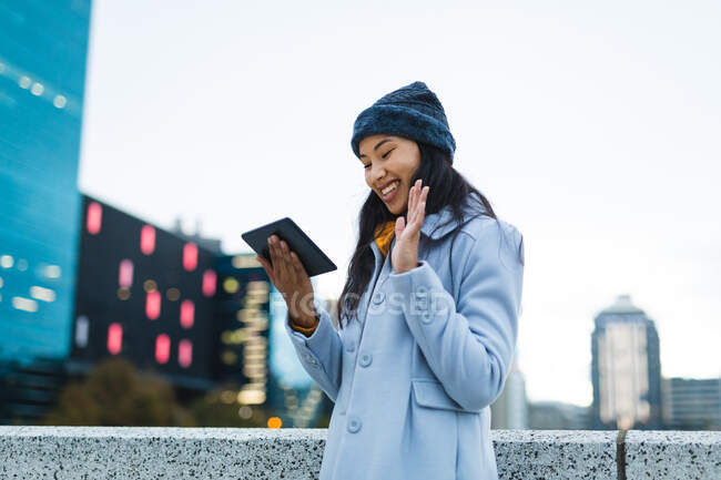 Asiatin mit Tablet und lächelnd auf der Straße. Unabhängige junge Frau in der Stadt unterwegs. — Stockfoto