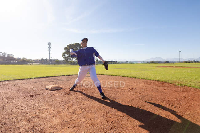 Mixed race female baseball player on sunny baseball field throwing ball during game. female baseball team, sports training and game tactics. — Stock Photo