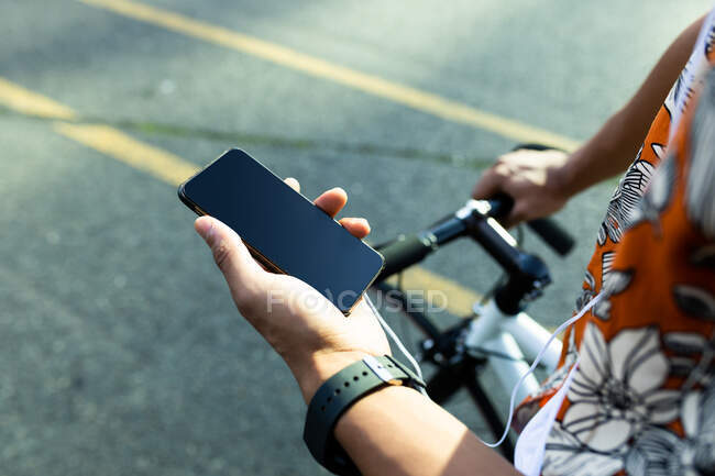 Mann in der Stadt sitzt auf Fahrrad und nutzt Smartphone. digitaler Nomade unterwegs, unterwegs in der Stadt. — Stockfoto