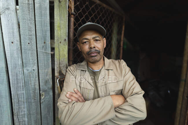 Porträt eines afrikanisch-amerikanischen Gärtners mit verschränkten Händen, der im Gartencenter in die Kamera blickt. Fachkraft in der Bonsai-Gärtnerei, selbstständiger Gartenbaubetrieb. — Stockfoto