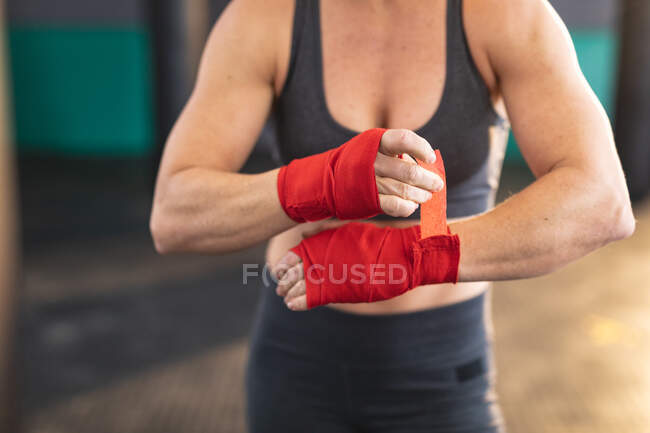 Femme forte faisant de l'exercice au gymnase, enveloppant les mains avec du ruban adhésif. musculation et fitness cross training pour la boxe. — Photo de stock