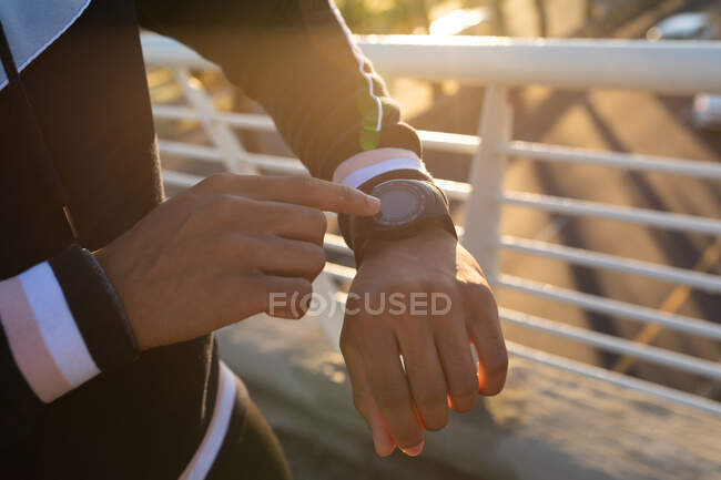 Uomo in forma che si allena in città controllando smartwatch in strada. fitness e stile di vita urbano attivo all'aperto. — Foto stock