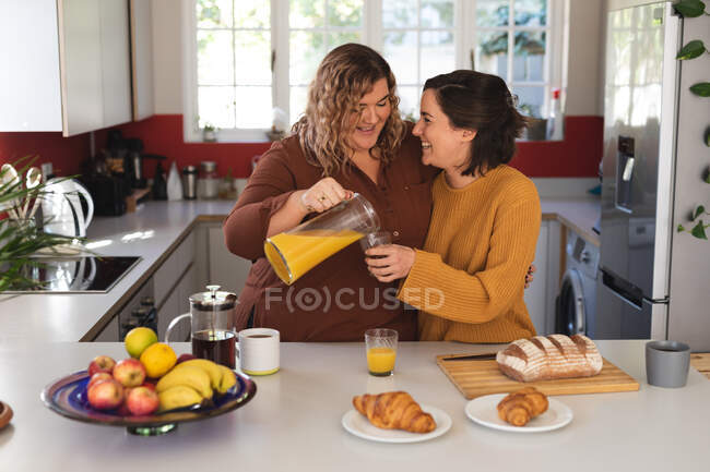 Couple lesbien souriant et préparant le petit déjeuner en cuisine. mode de vie domestique, passer du temps libre à la maison. — Photo de stock