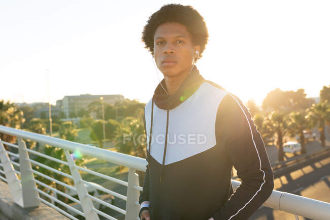 Portrait of fit african american man exercising in city wearing earphones in the street. fitness and active urban outdoor lifestyle. — Stock Photo