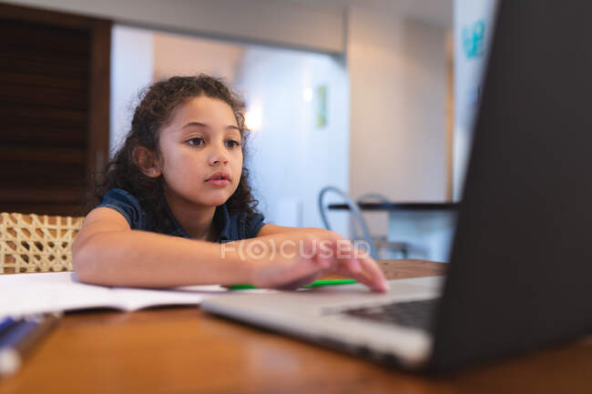 Mädchen mit gemischter Rasse, die am Tisch sitzt und Laptop benutzt. Lebensstil und hochwertige Zeit zu Hause verbringen. — Stockfoto