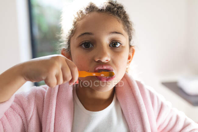 Porträt eines Mädchens mit gemischter Rasse beim Zähneputzen im Badezimmer. Lebensstil und hochwertige Zeit zu Hause verbringen. — Stockfoto