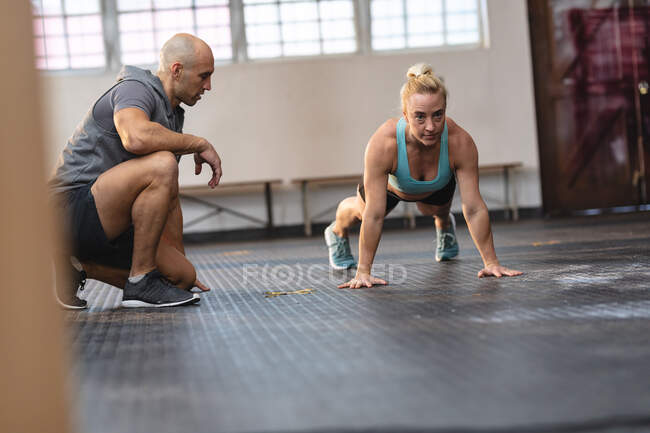 Caucasian male trainer instructing woman exercising at gym, doing press ups. strength and fitness cross training for boxing. — Stock Photo